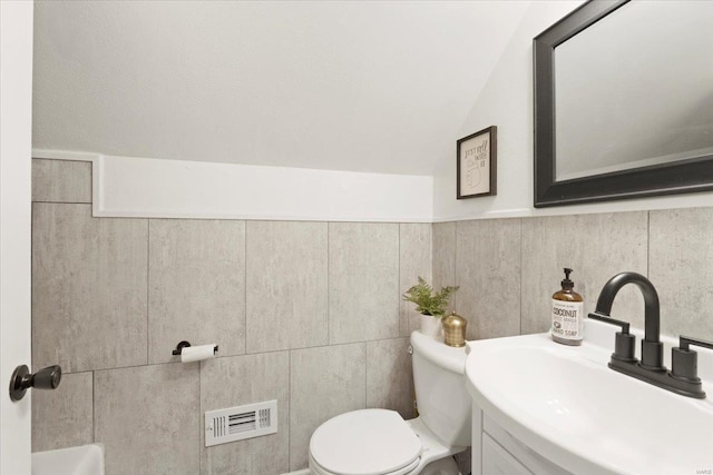 bathroom featuring visible vents, lofted ceiling, toilet, and vanity