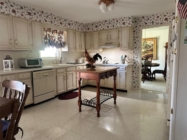 kitchen featuring decorative backsplash, white dishwasher, light countertops, stainless steel microwave, and under cabinet range hood