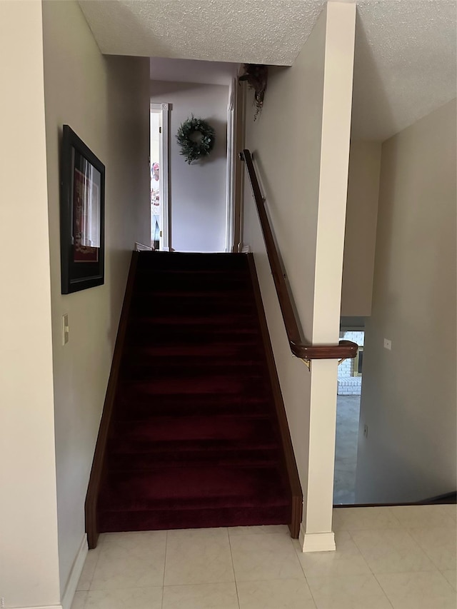 stairs with a textured ceiling and baseboards