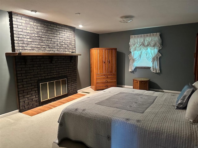 carpeted bedroom featuring baseboards and a brick fireplace