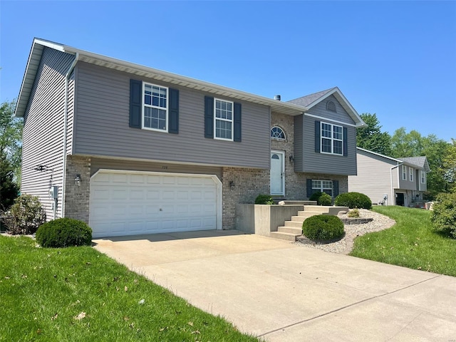 split foyer home with an attached garage, a front yard, driveway, and brick siding
