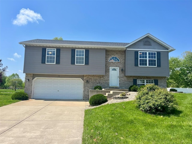 raised ranch with brick siding, an attached garage, driveway, and a front yard