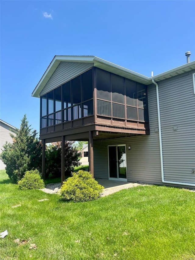 rear view of house featuring a lawn, a sunroom, and a patio