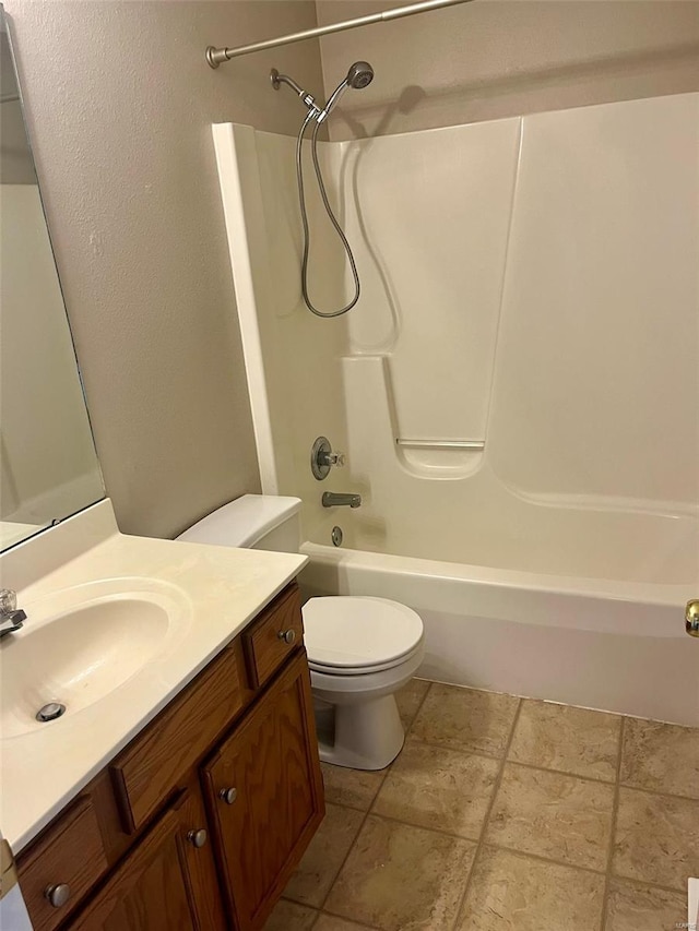 full bath featuring toilet, stone tile flooring, bathtub / shower combination, and vanity