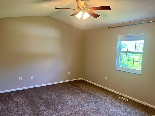 spare room featuring a ceiling fan, visible vents, lofted ceiling, and dark colored carpet