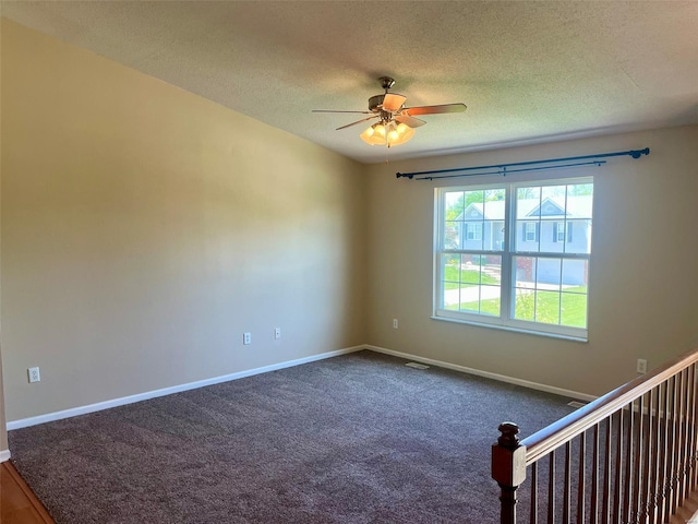 empty room with carpet floors, a ceiling fan, a textured ceiling, and baseboards