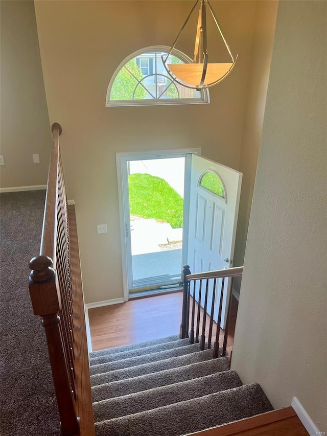 stairway with baseboards, a high ceiling, and wood finished floors
