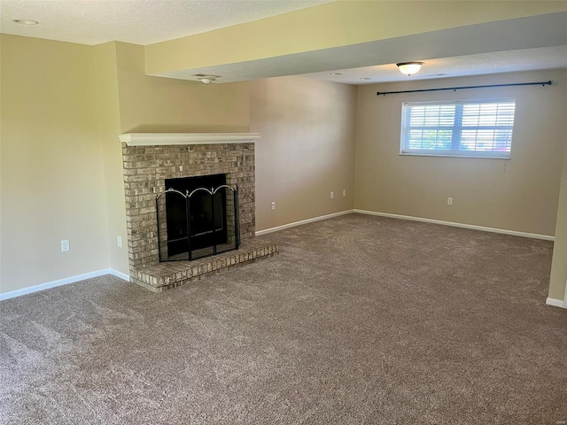 unfurnished living room with carpet flooring, a textured ceiling, baseboards, and a fireplace