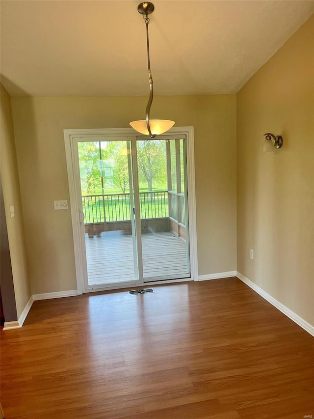 unfurnished dining area with baseboards, visible vents, and wood finished floors