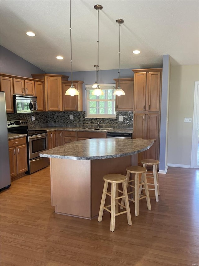 kitchen featuring decorative backsplash, a kitchen island, dark countertops, a kitchen breakfast bar, and stainless steel appliances