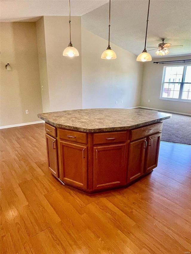 kitchen with decorative light fixtures, open floor plan, light wood finished floors, and a center island