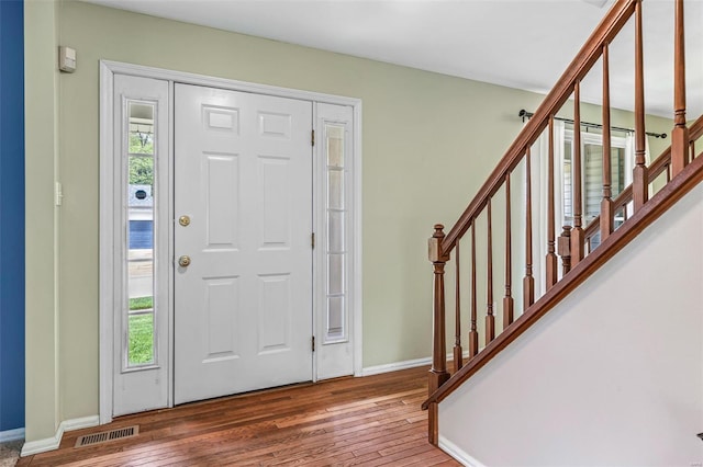 foyer entrance featuring stairway, baseboards, wood-type flooring, and visible vents