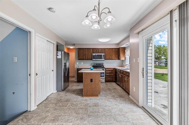 kitchen with dark brown cabinetry, a kitchen island, light countertops, a notable chandelier, and stainless steel appliances
