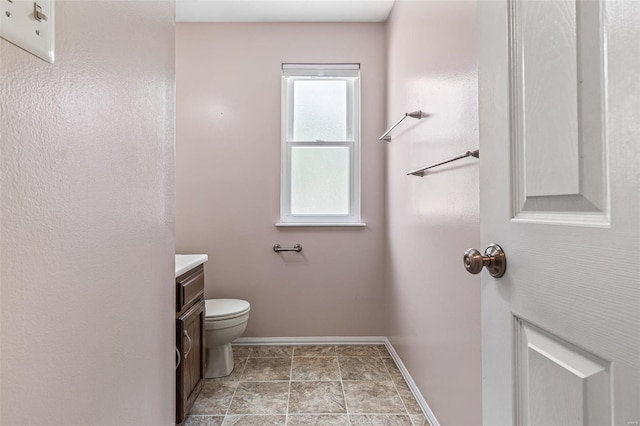 bathroom with toilet, baseboards, and vanity