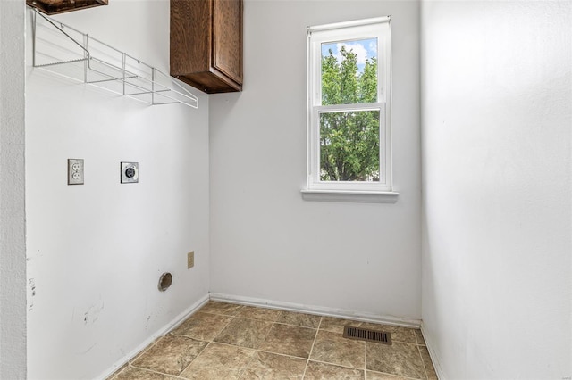clothes washing area with visible vents, baseboards, cabinet space, electric dryer hookup, and stone finish flooring