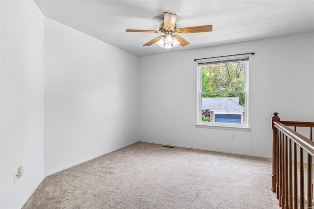 carpeted spare room featuring baseboards, ceiling fan, and visible vents