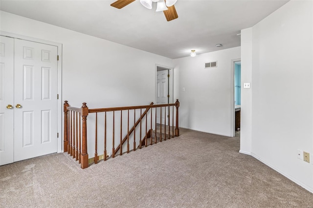 corridor with carpet floors, baseboards, an upstairs landing, and visible vents