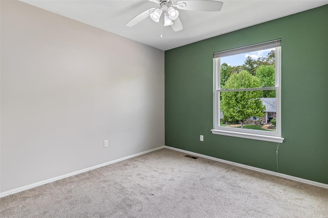 carpeted spare room featuring visible vents, baseboards, and ceiling fan
