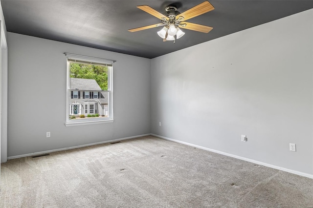 carpeted spare room featuring visible vents, baseboards, and ceiling fan
