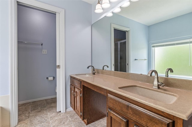 full bathroom with a sink, baseboards, a shower with shower door, and double vanity