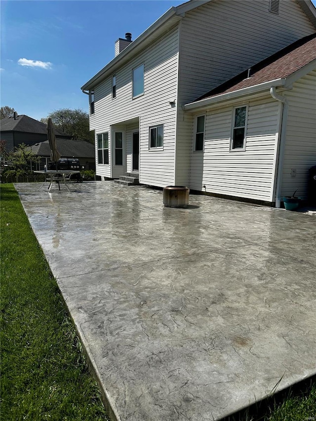 rear view of property with a chimney and a patio area