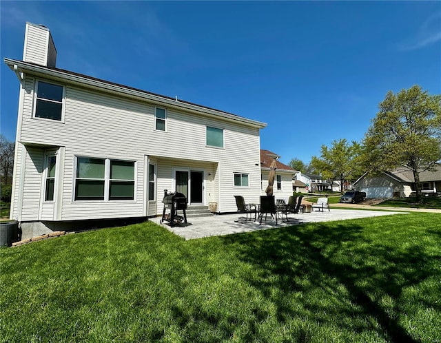 rear view of house with a lawn, cooling unit, a chimney, and a patio area