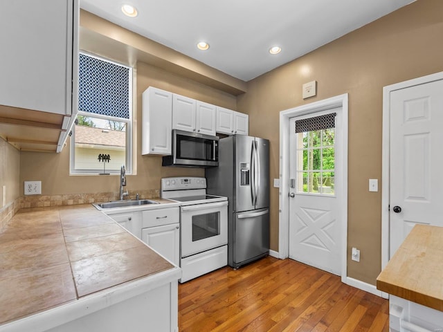 kitchen featuring a sink, white cabinets, stainless steel appliances, and light wood finished floors