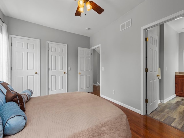 bedroom featuring a ceiling fan, baseboards, visible vents, and wood finished floors