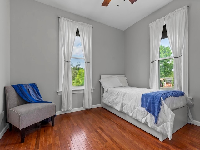bedroom with baseboards, a ceiling fan, hardwood / wood-style floors, and multiple windows