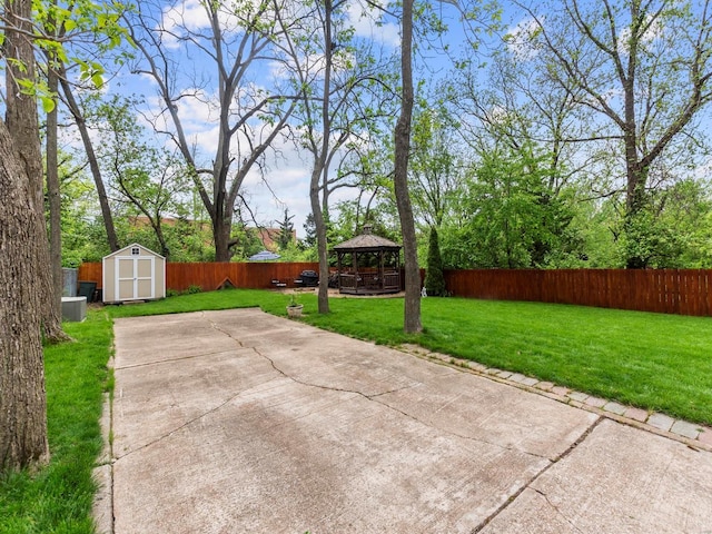 view of patio with a storage unit, a fenced backyard, an outbuilding, and a gazebo
