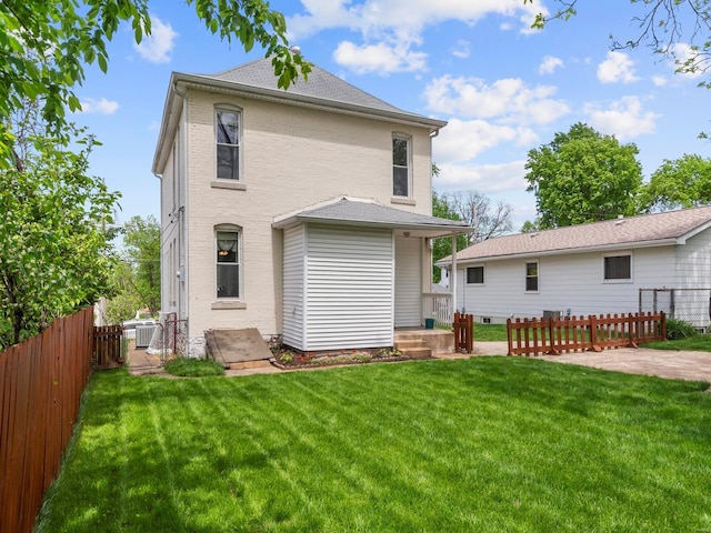 back of property featuring brick siding, fence, and a yard