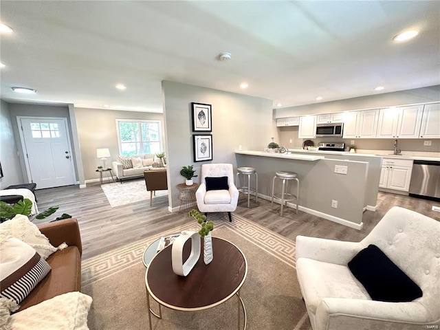 living room featuring baseboards, recessed lighting, and light wood-style flooring