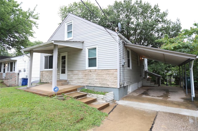 view of front of home featuring an attached carport, a front lawn, driveway, and stone siding