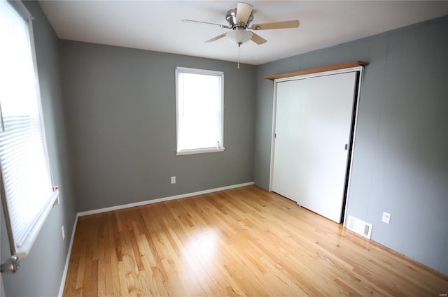 unfurnished bedroom with a closet, ceiling fan, light wood finished floors, baseboards, and visible vents