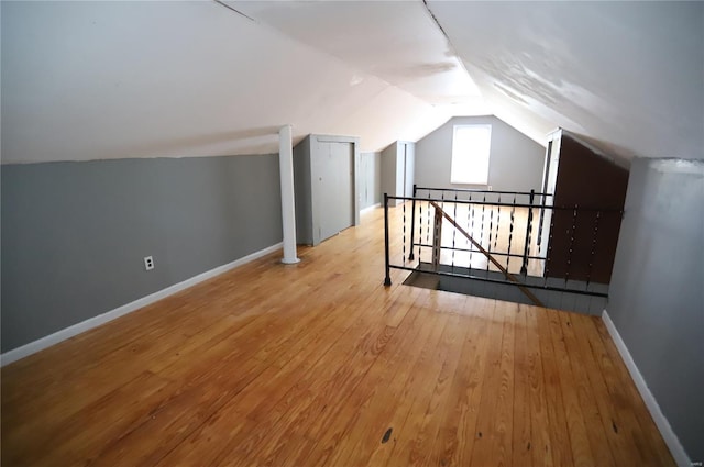 additional living space with hardwood / wood-style floors, vaulted ceiling, and baseboards