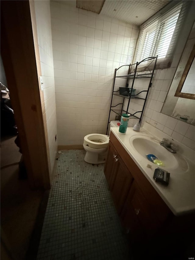 bathroom featuring tile patterned floors, vanity, toilet, and tile walls