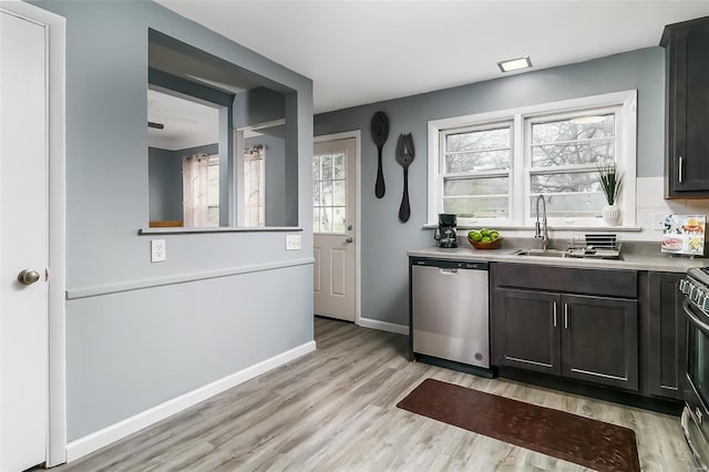 kitchen featuring baseboards, light countertops, a sink, light wood finished floors, and stainless steel appliances