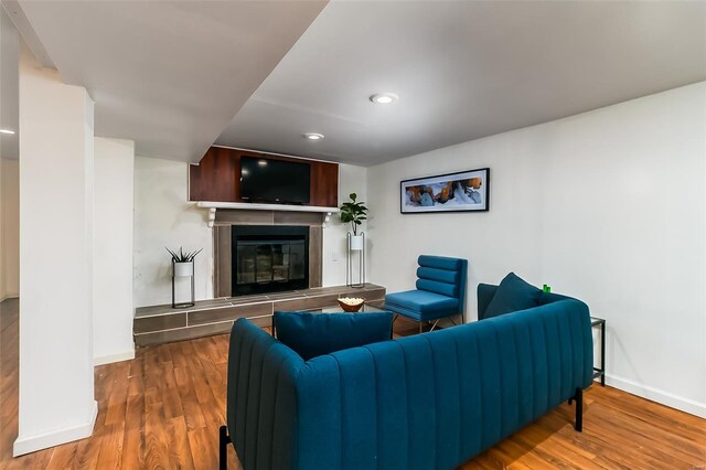 living area with a tiled fireplace, baseboards, recessed lighting, and wood finished floors
