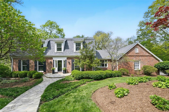 view of front of home featuring brick siding, a shingled roof, and a front lawn