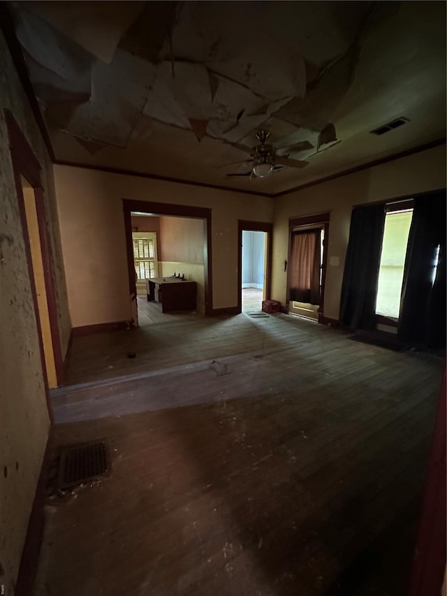 unfurnished room featuring a ceiling fan, visible vents, wood finished floors, and baseboards