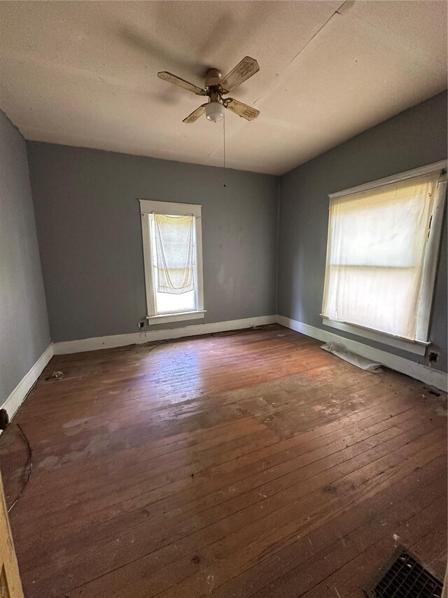 empty room featuring baseboards, hardwood / wood-style flooring, a ceiling fan, and a textured ceiling