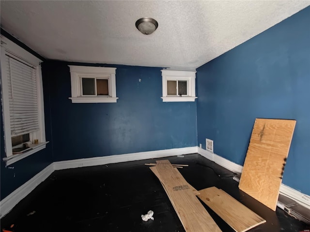 spare room with baseboards, cooling unit, and a textured ceiling