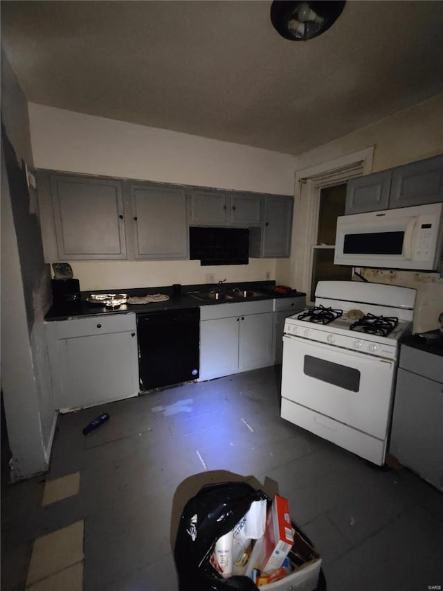 kitchen featuring gray cabinetry, a sink, dark countertops, and white appliances