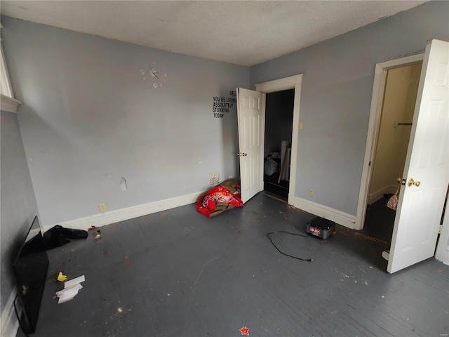 unfurnished bedroom with a textured ceiling and baseboards