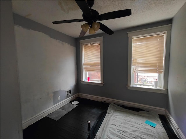 empty room with a ceiling fan, a textured ceiling, and baseboards