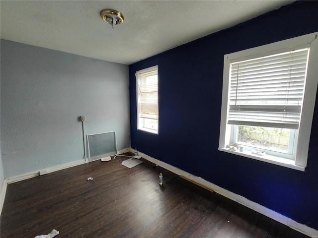 empty room with baseboards, plenty of natural light, and wood finished floors