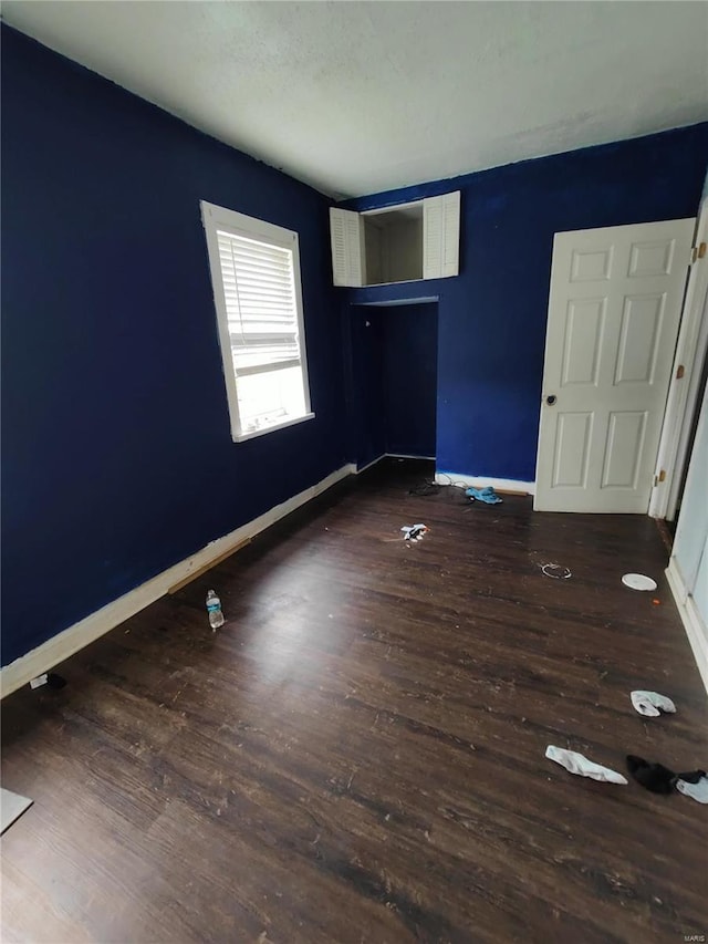 unfurnished room featuring dark wood-style flooring and baseboards