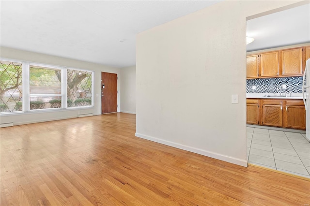 unfurnished living room featuring baseboards and light wood-type flooring