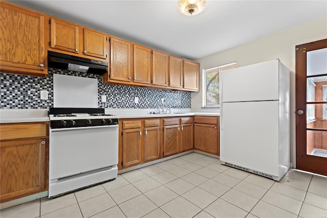 kitchen featuring light countertops, a sink, under cabinet range hood, and white appliances