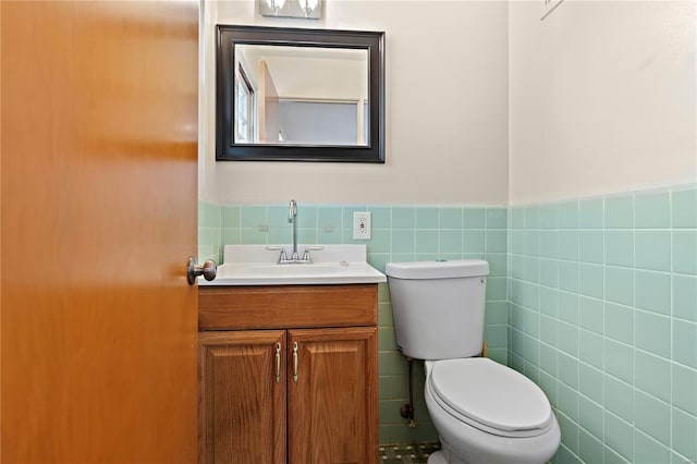 bathroom featuring toilet, a wainscoted wall, tile walls, and vanity